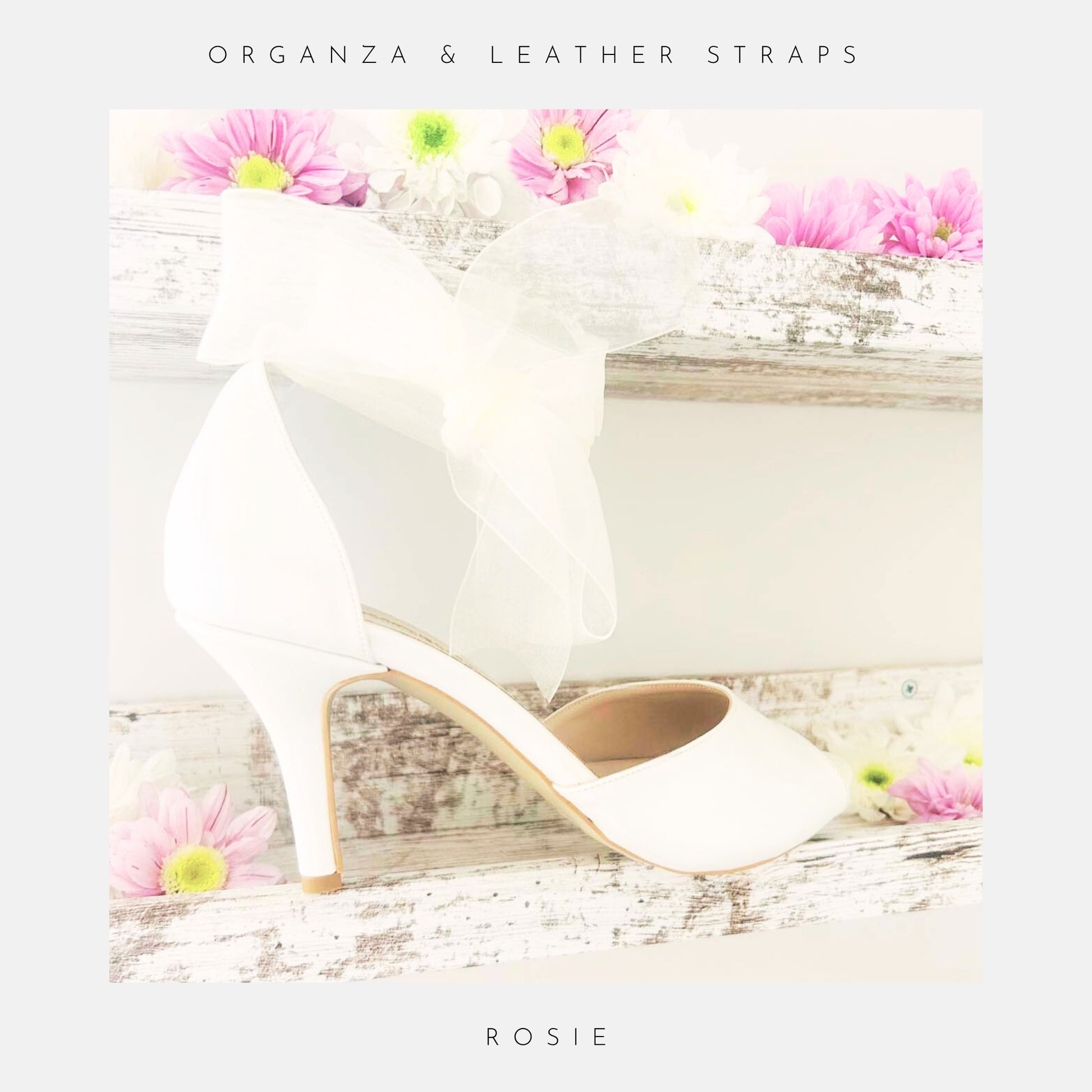 Ivory high-heeled shoe with a decorative bow on a wooden surface with flowers.