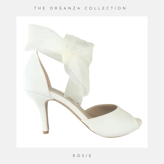 Ivory high-heeled shoe with ruffled design on a light grey background, featuring 'The Organza Collection' and 'Rosie'.