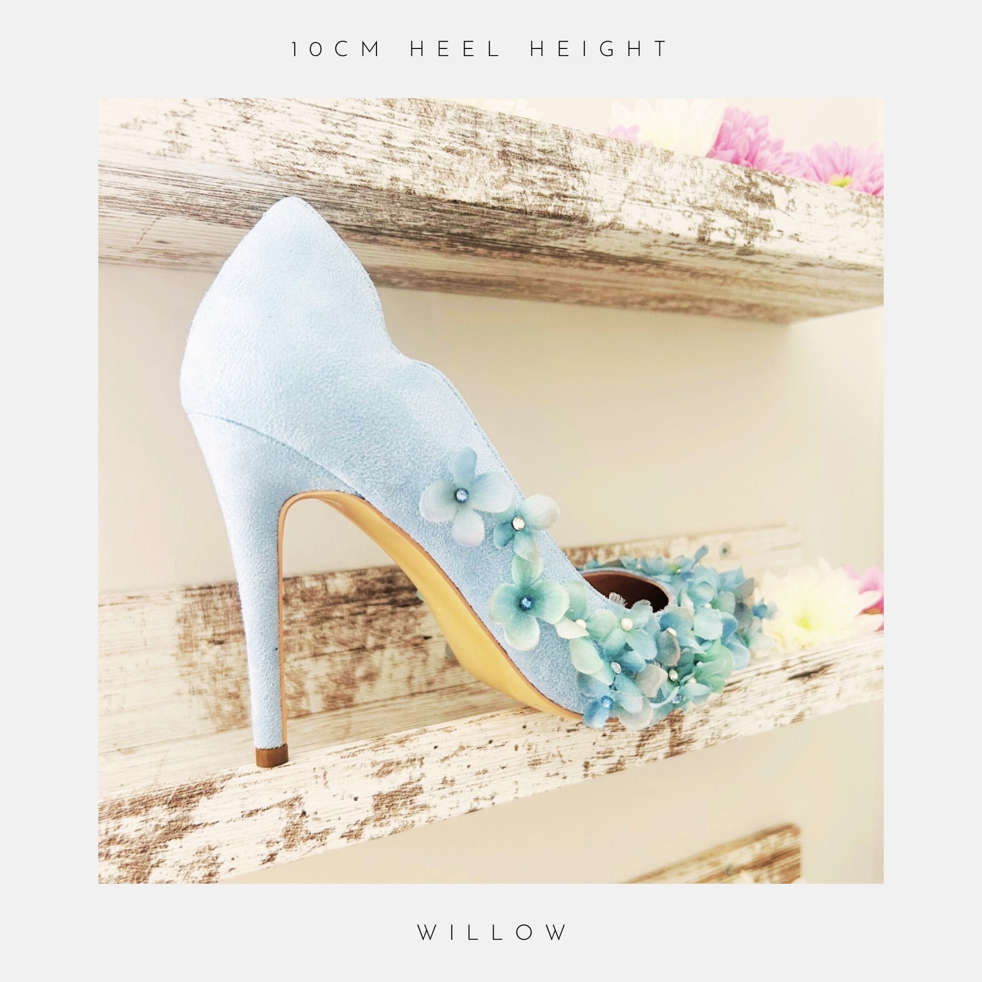 Light blue high-heeled wedding shoes with floral design on a wooden shelf with flowers.