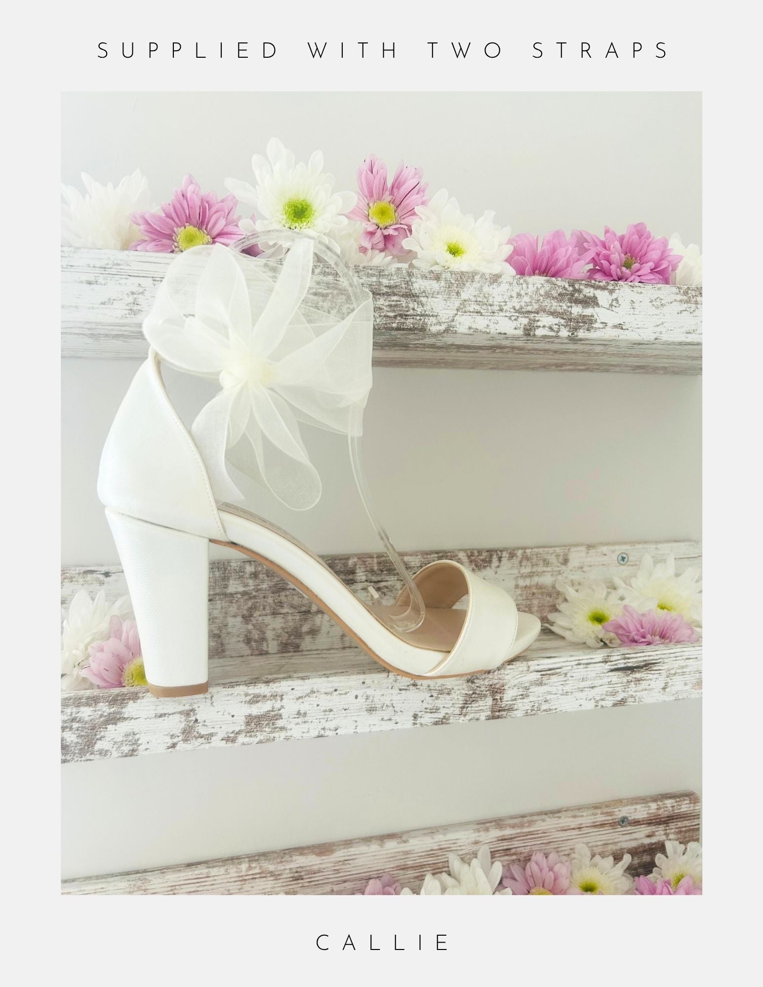 Ivory high-heeled shoe with an organza bow, placed on a wooden surface with flowers.