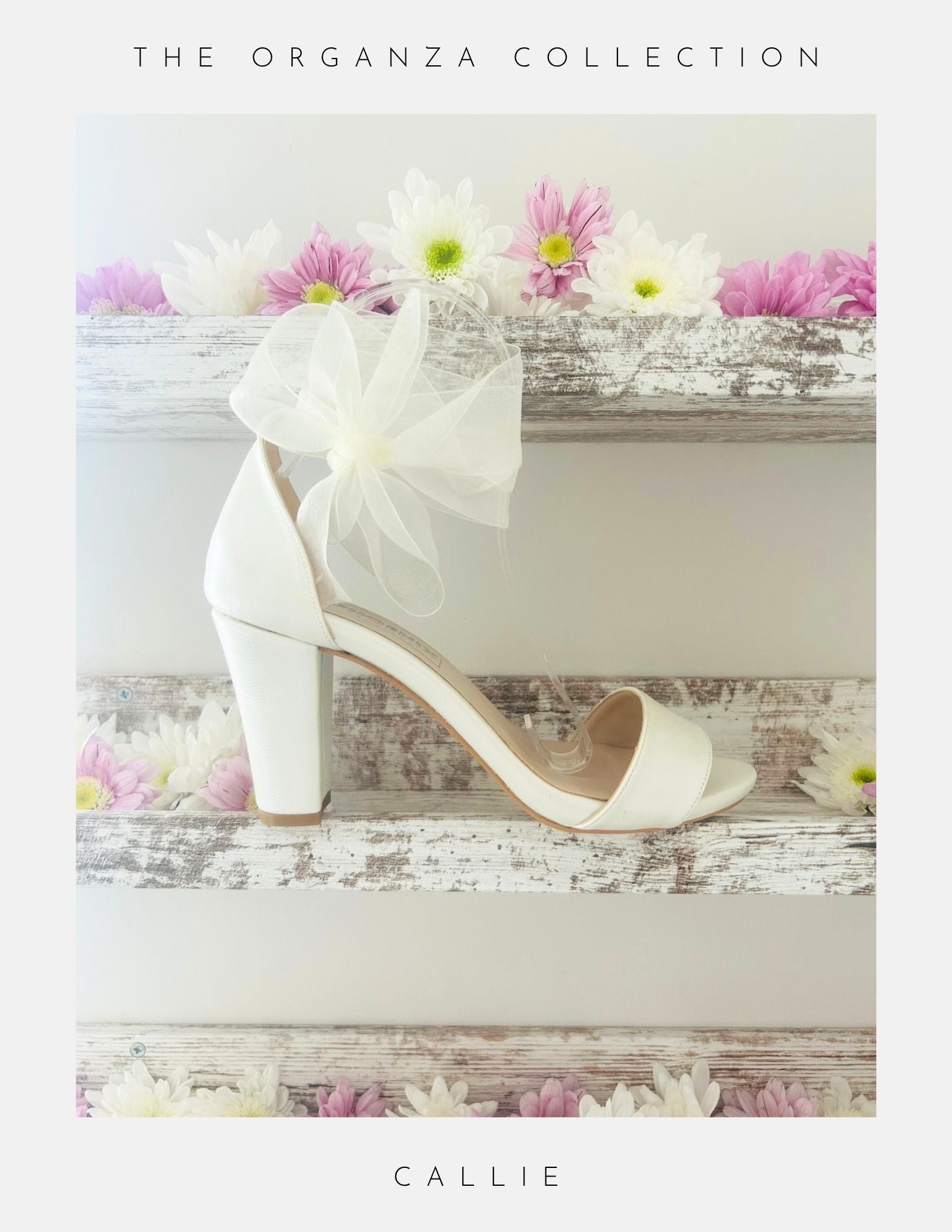 Ivory high-heeled shoe with a bow on a wooden surface with flowers, labeled 'The Organza Collection' and 'Callie'.