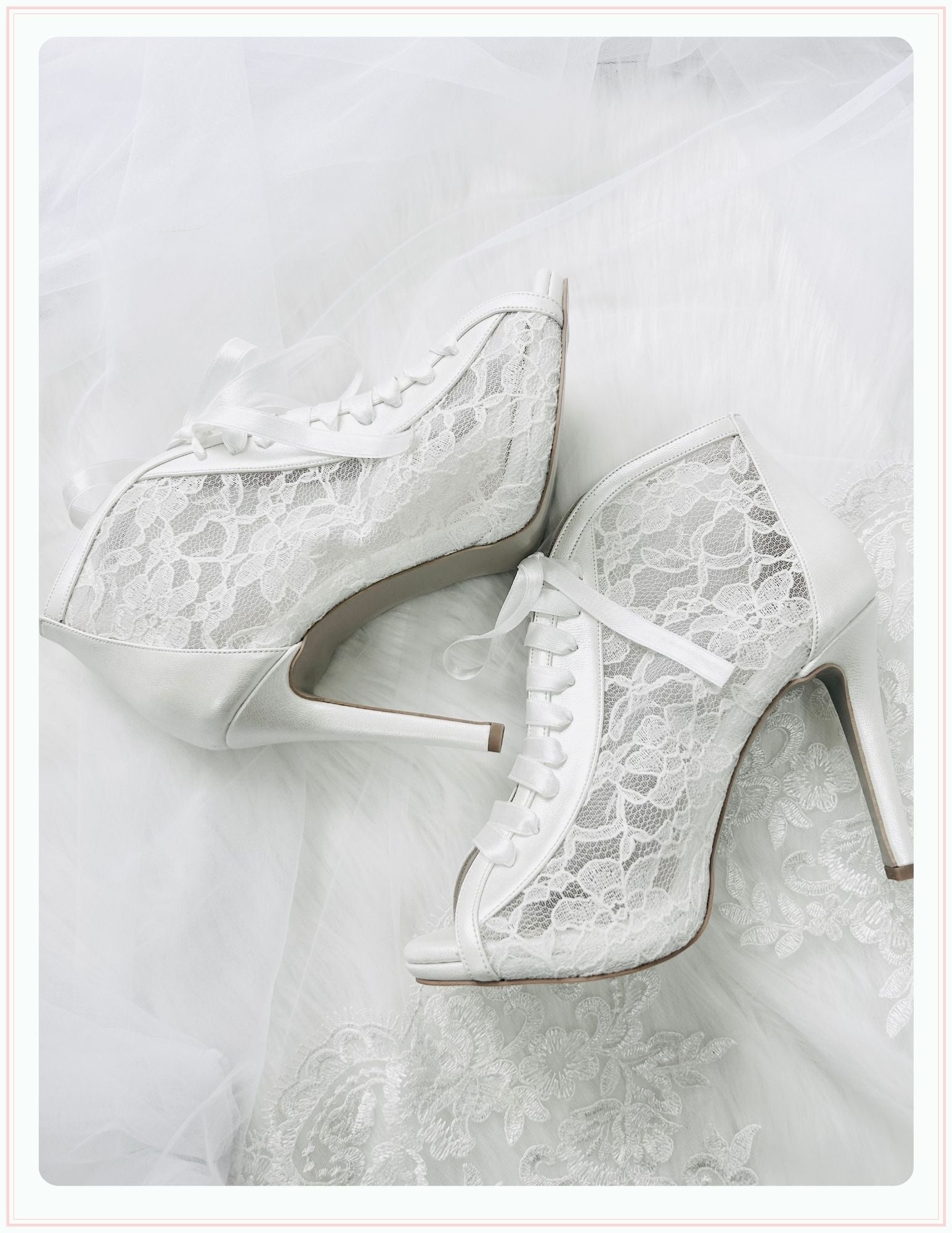 The Phoenix England Chantilly Wedding Shoes feature white Chantilly lace, ribbon laces, and peep toes, beautifully displayed on sheer, delicate fabric.