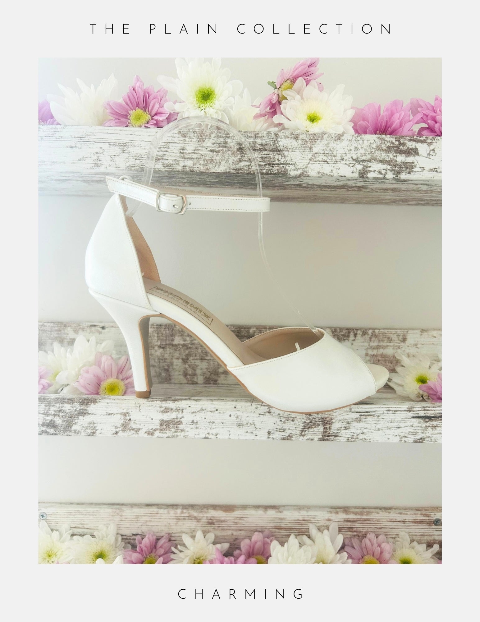 Ivory high-heeled peep toe bridal shoe on a wooden surface with flowers, labelled 'The Plain Collection'.