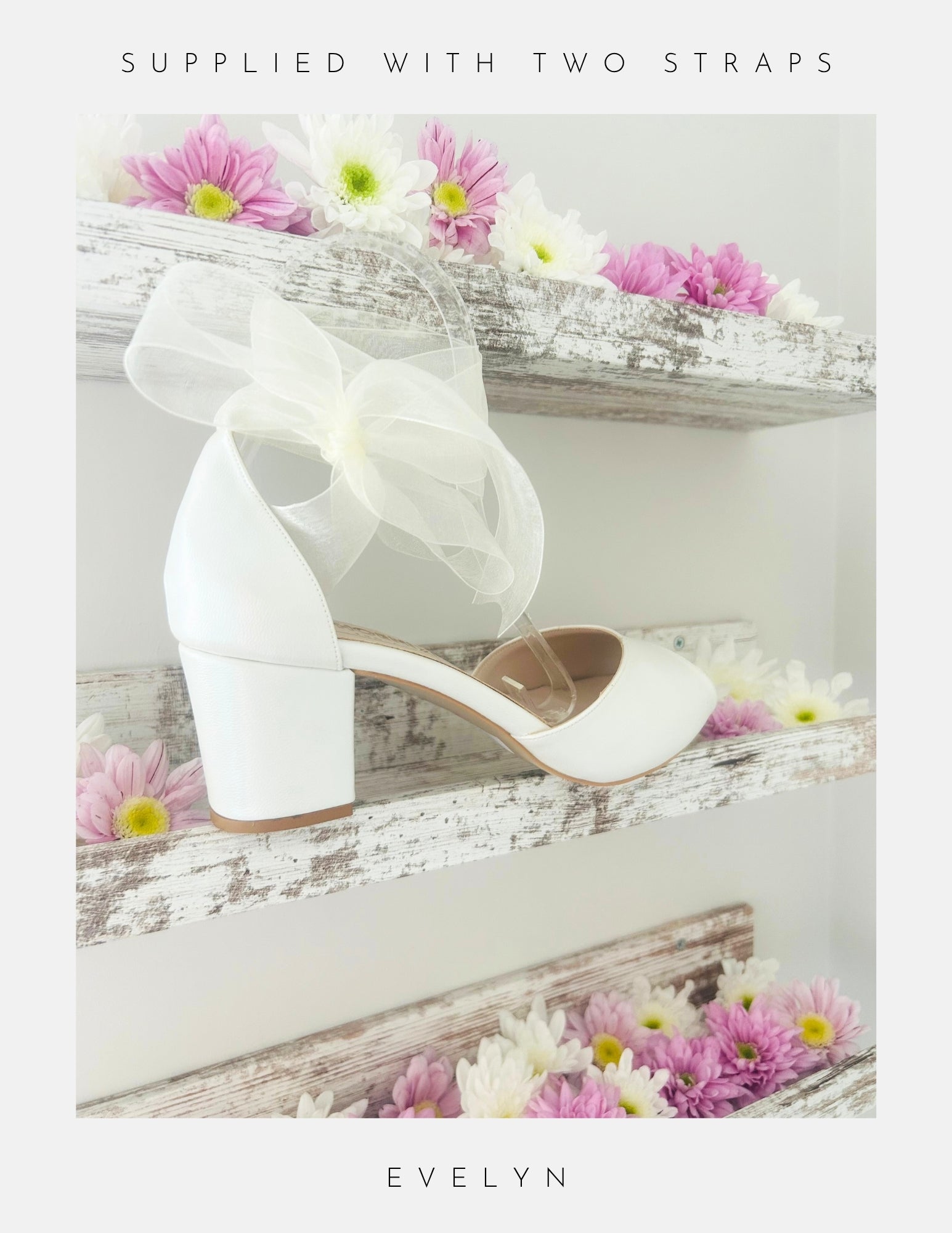 Ivory wedding shoes with a bow on a wooden surface with flowers.