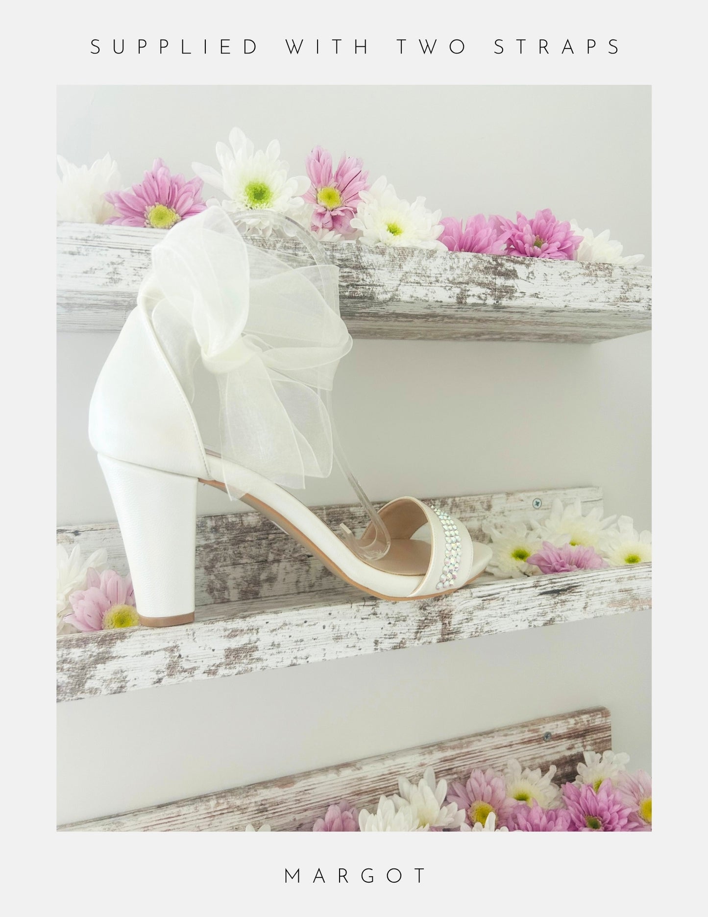 Ivory high-heeled shoe with a bow on a wooden surface with flowers, branded 'MARGOT'.