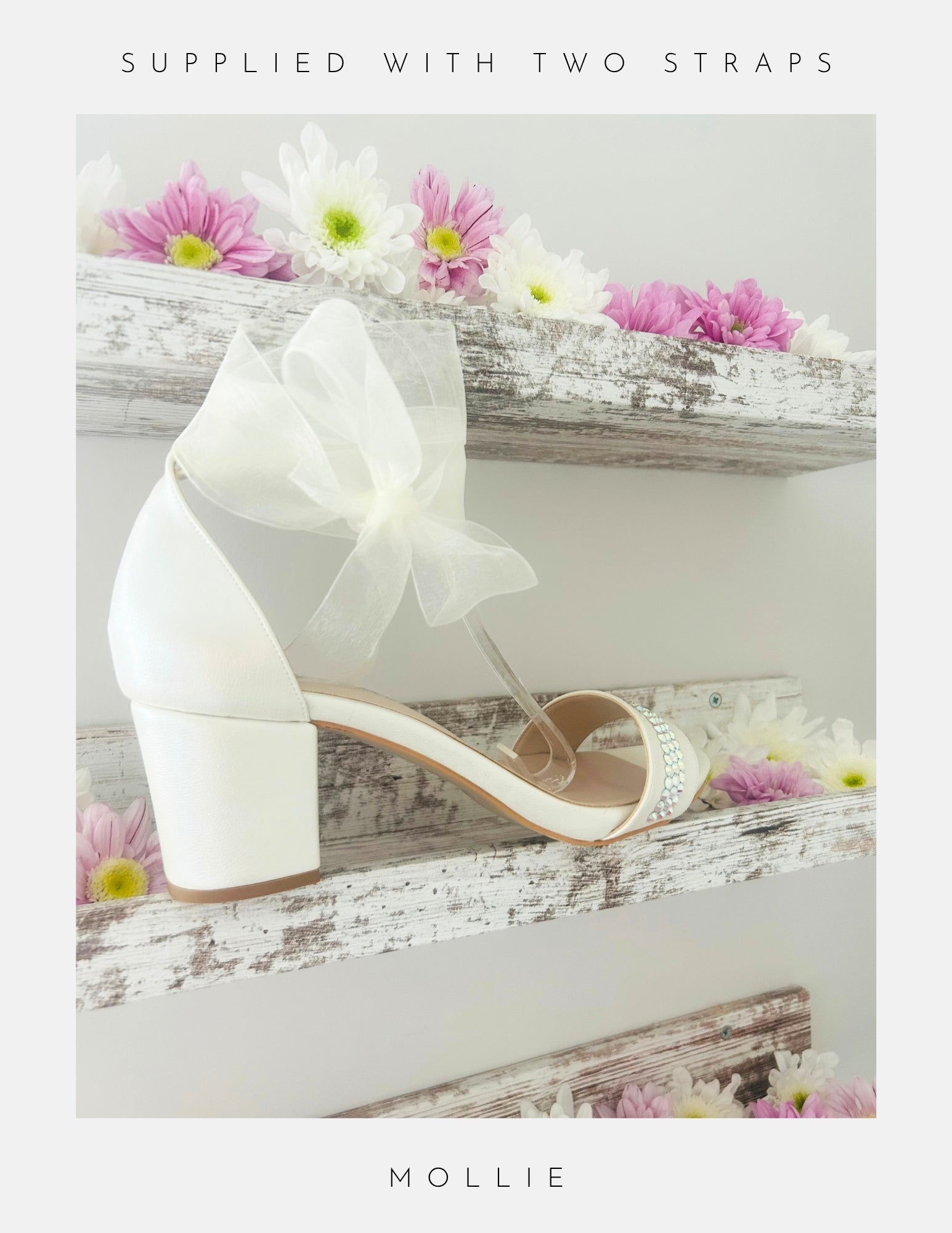 Ivory wedding shoe with an organza bow on a wooden surface with flowers