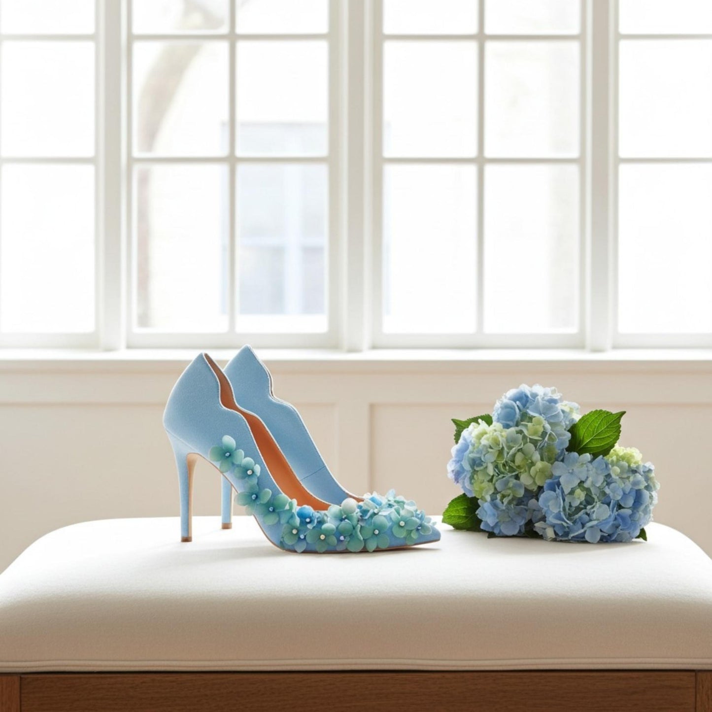Pair of blue bridal heels with flowers, pearls and crystals with a wedding bouquet of hydrangeas next to it.